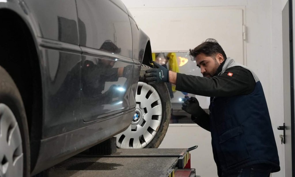 Prüfingenieur kontrolliert ein älteres Auto bei der Hauptuntersuchung