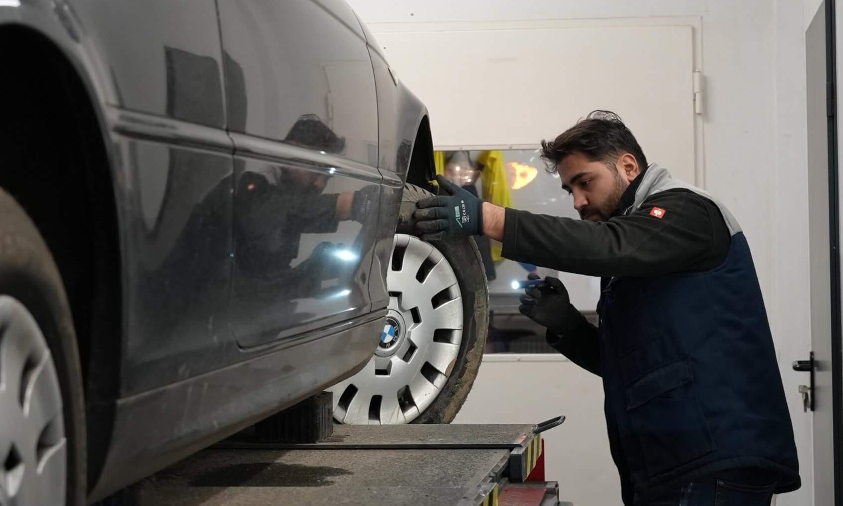 Prüfingenieur kontrolliert ein älteres Auto bei der Hauptuntersuchung